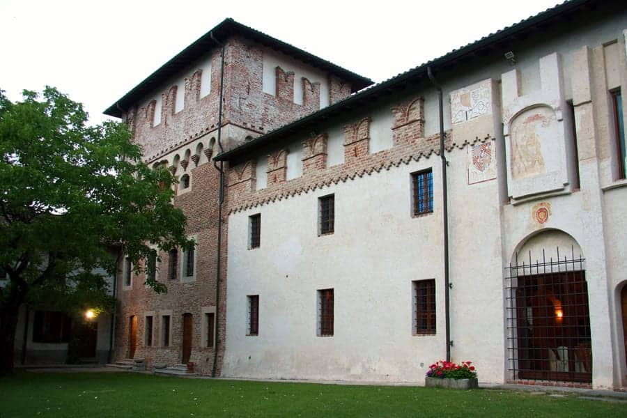 Castello di Vespolate, Vespolate, Piemonte: exterior, the brick keep and the frescoed inner wing seen across the lawn of the inner court in warm evening light.