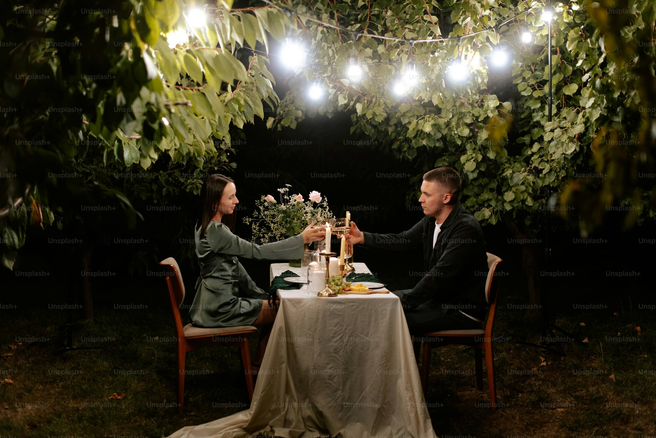 A couple sitting close at a dinner table, candles lit, the evening around them.